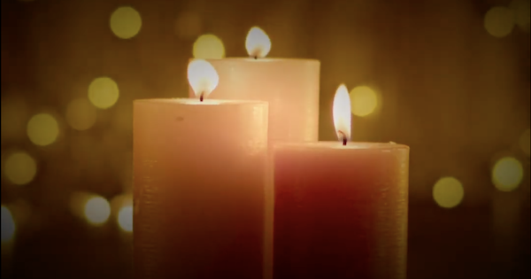 Three lit white candles against an atmospheric dark backdrop