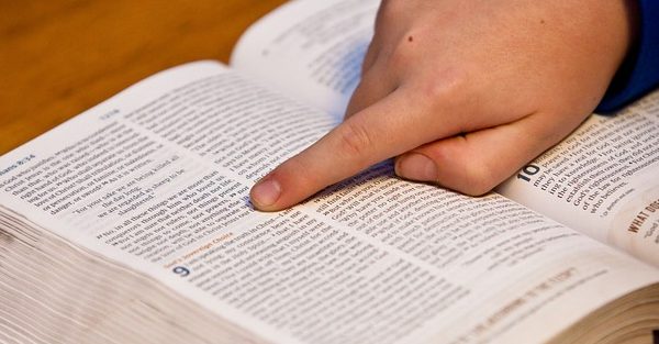 A hand pointing to a verse in the Bible