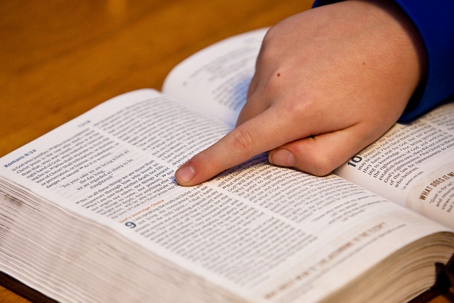 A hand pointing to a verse in the Bible