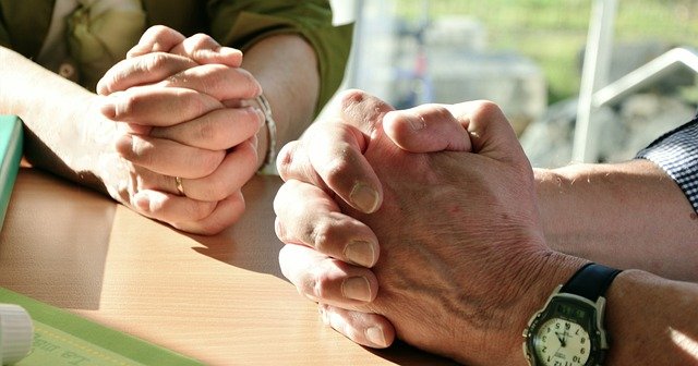 Two people's hands clasped together in prayer