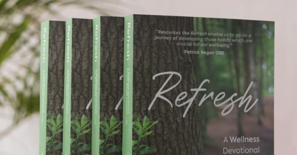 Four copies of Jo Acharya's book 'Refresh: a wellness devotional for the whole Christian life' lined up on a shelf with a leafy fern