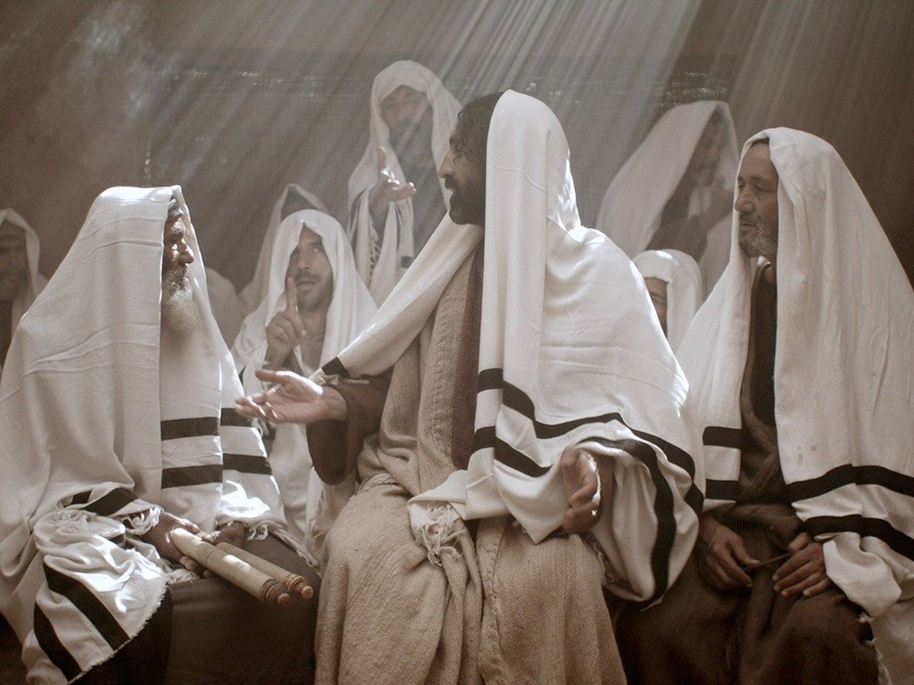 Jesus teaching in the synagoge, with several men wearing white prayer shawls (tallits) on their heads