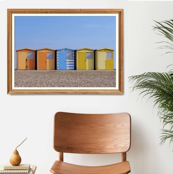 Beach huts and happiness print framed on wall with chair and plant in front